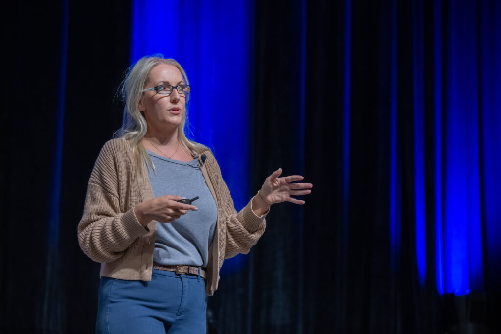 Image of women speaking on stage with a blue background